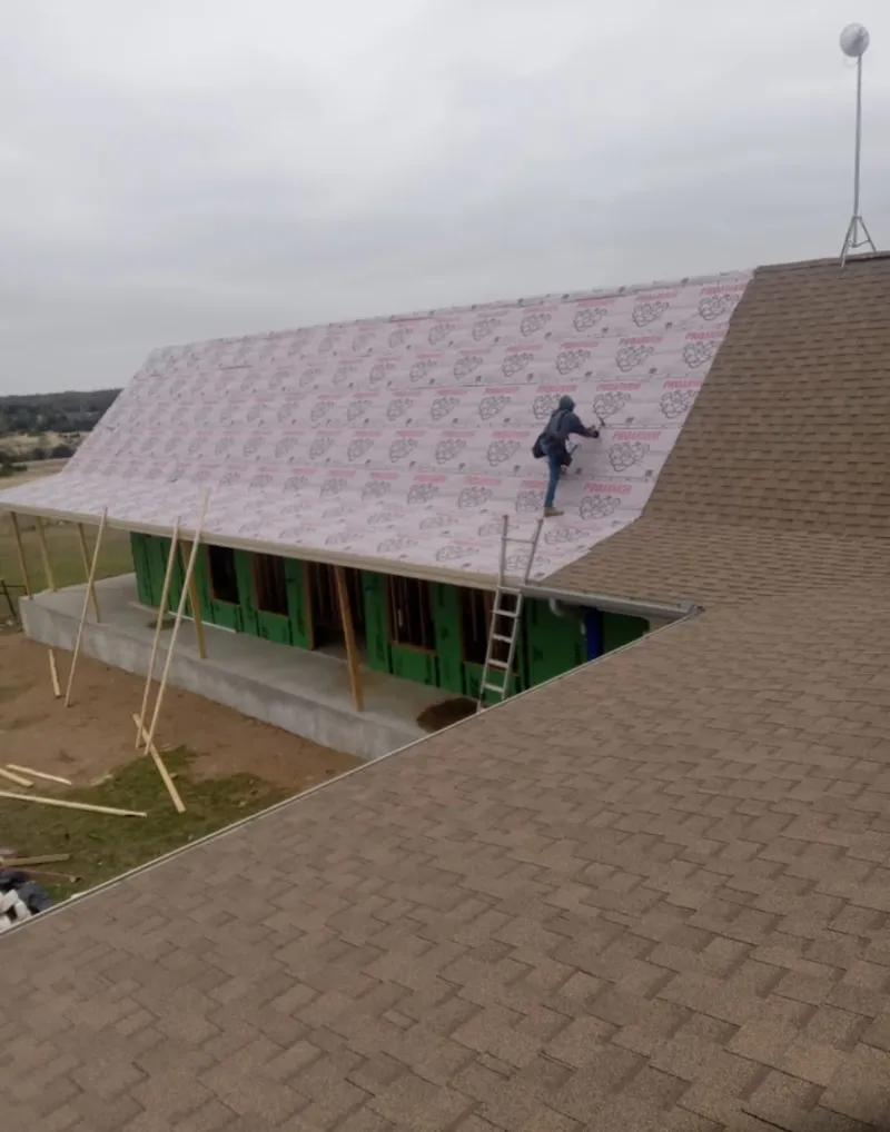 Worker preparing underlayment for a metal roof installation in Maitland